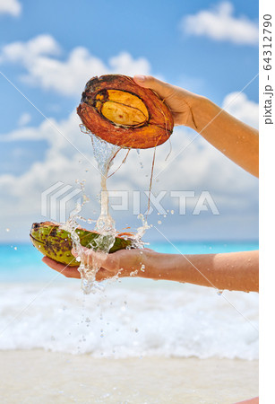 Woman splashing water with coconut on beach 64312790