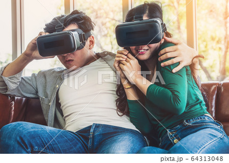 Happy couple watching video in virtual reality VR 64313048