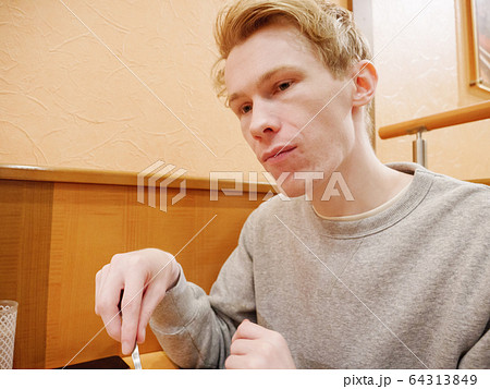 A sad young man alone in a restaurant 64313849