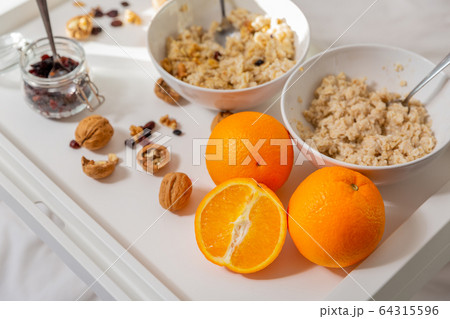 Happy mom and daughter have healthy breakfast on bed in a light bedroom on a sunny morning. Orange 64315596