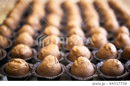 Lots of delicious fresh chocolate muffins muffins on a tray, background, copy space, dessert, manufacturing 64317739
