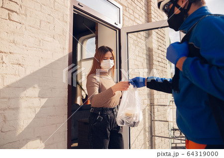 Contacless delivery service during quarantine. Man delivers food and shopping bags during isolation Contacless delivery service during quarantine. Man delivers food and shopping bags during isolation 64319000