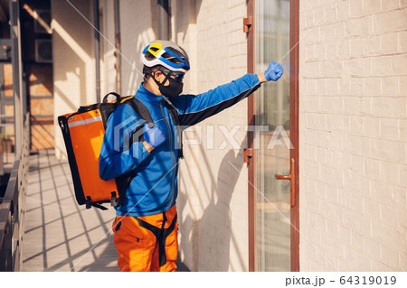 Contacless delivery service during quarantine. Man delivers food and shopping bags during isolation Contacless delivery service during quarantine. Man delivers food and shopping bags during isolation 64319019