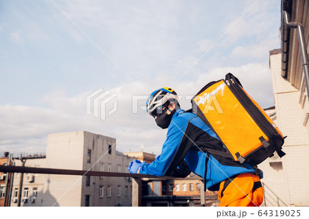 Contacless delivery service during quarantine. Man delivers food and shopping bags during isolation Contacless delivery service during quarantine. Man delivers food and shopping bags during isolation 64319025