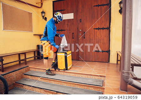 Contacless delivery service during quarantine. Man delivers food and shopping bags during isolation 64319059