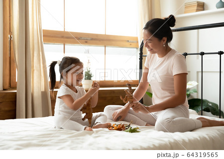 Asian daughter and mother sitting on bed play with dinosaurs Asian daughter and mother sitting on bed play with dinosaurs 64319565