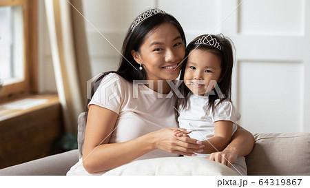 Beautiful mother cuddles adorable preschool daughter happy family portrait Beautiful mother cuddles adorable preschool daughter happy family portrait 64319867