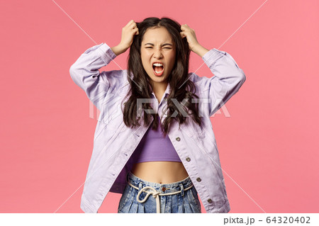 Portrait of furious young pissed-off girl losing her mind, distressed pull hair from head and screaming, grimacing look angry and hateful, standing stressed over pink background Portrait of furious young pissed-off girl losing her mind, distressed pull hair from head and screaming, grimacing look angry and hateful, standing stressed over pink background 64320402