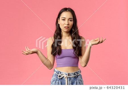 So what. Portrait of careless arrogant stylish asian girl shrugging, raise hands clueless and look camera with skeptical, unimpressed expression, dont care and not see any point, pink background 64320431