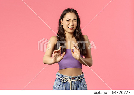No thank you, gross. Picky stylish young female step away, grimacing from disgust and shaking raised hands, refuse from stinky smelly awful food, express dislike and aversion, stand pink background No thank you, gross. Picky stylish young female step away, grimacing from disgust and shaking raised hands, refuse from stinky smelly awful food, express dislike and aversion, stand pink background 64320723