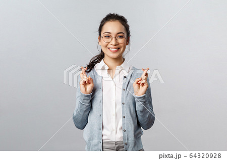 Emotions, people and lifestyle concept. Optimistic happy, smiling asian girl having faith all be alright, cross fingers good luck, hopeful anticipating positive results, pleading over grey background Emotions, people and lifestyle concept. Optimistic happy, smiling asian girl having faith all be alright, cross fingers good luck, hopeful anticipating positive results, pleading over grey background 64320928