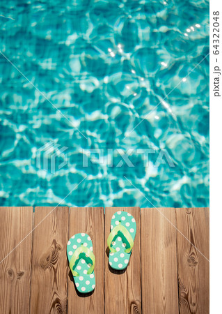 Flip-flops on wooden background near swimming pool 64322048