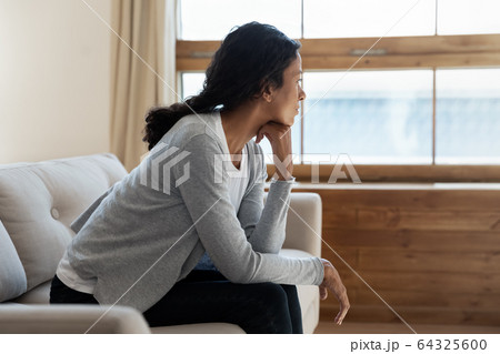 Unhappy african american girl sit on sofa at home Unhappy african american girl sit on sofa at home 64325600