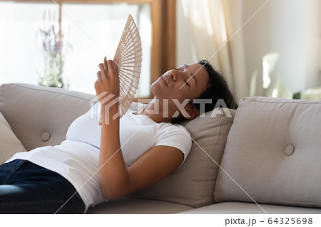 Exhausted african american woman hold fan in hand Exhausted african american woman hold fan in hand 64325698
