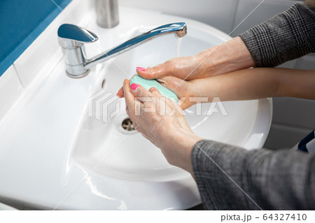 Mother washing hands her son carefully in bathroom close up. Prevention of infection and pneumonia virus spreading Mother washing hands her son carefully in bathroom close up. Prevention of infection and pneumonia virus spreading 64327410