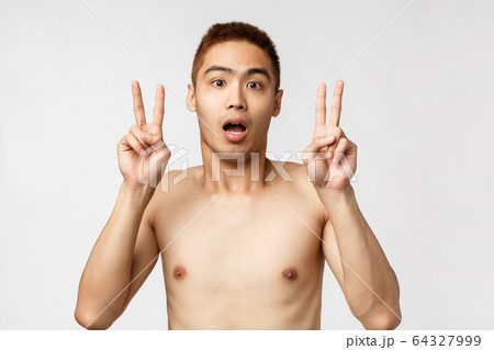 Beauty, people and home concept. Shocked young asian man with naked torso, showing peace sign or quotation marks, gasping startled, hear strange news, express disbelief, white background 64327999