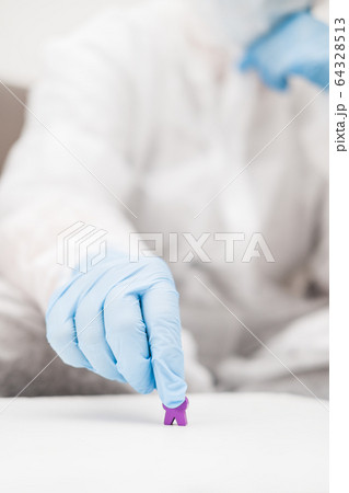 Two people in protective white translucent suit, blue rubber gloves, medical mask sit on sofa at home and play board games, roll dice. Stay home during coronavirus pandemic covid. 64328513