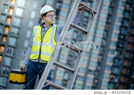 Worker man carrying aluminium ladder and tool box Worker man carrying aluminium ladder and tool box 64329428