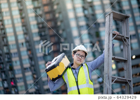 Worker man carrying aluminium ladder and tool box 64329429