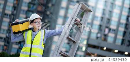 Worker man carrying aluminium ladder and tool box Worker man carrying aluminium ladder and tool box 64329430