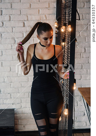 Portrait of amazing stylish young woman, posing at loft style room. Stunning long legs, perfect and attractive figure. 64330357
