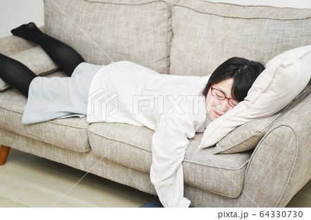 ソファーの上で寝る女性 64330730