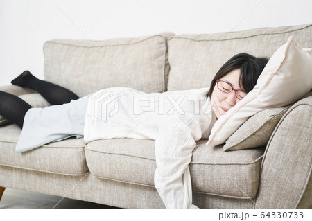 ソファーの上で寝る女性 ソファーの上で寝る女性 64330733