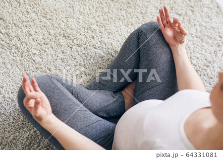 Pregnant woman meditating in lotus position 64331081