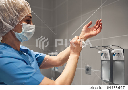 Close-up of a doctor washing his hands using a disinfectant dispenser. Close-up of a doctor washing his hands using a disinfectant dispenser. 64333667