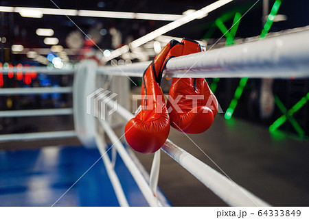 Pair of red boxing gloves hanging on a ropes 64333849