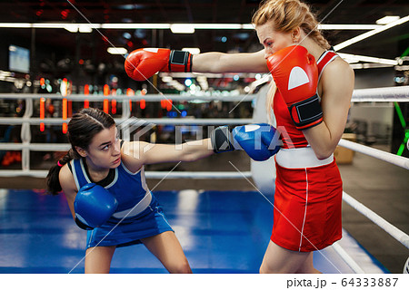 Women in red and blue gloves boxing on the ring 64333887