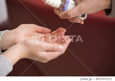 母親に除菌ジェルで手を消毒してもらう小学生手元 母親に除菌ジェルで手を消毒してもらう小学生手元 64344321