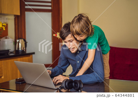 Man is trying to work from home because of the coronovirus epidemic, but his son is stopping him Man is trying to work from home because of the coronovirus epidemic, but his son is stopping him 64344801