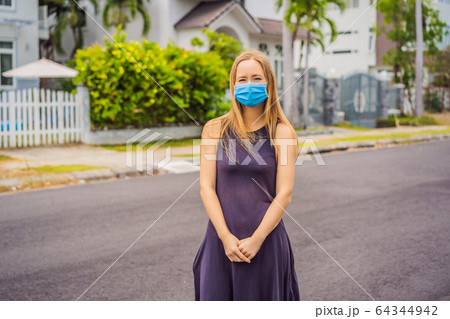 Woman in a small town in a medical mask because of a coronovirus epidemic Woman in a small town in a medical mask because of a coronovirus epidemic 64344942
