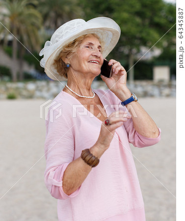 Aged woman talking on phone outdoors Aged woman talking on phone outdoors 64345887