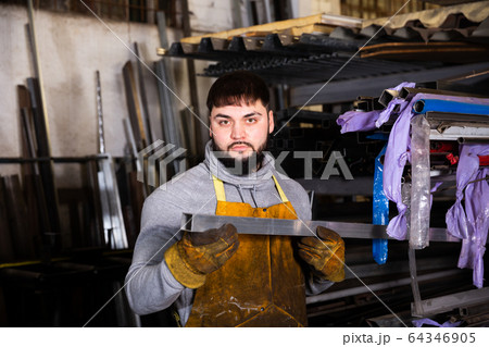 Worker with metal beams during work in workshop Worker with metal beams during work in workshop 64346905