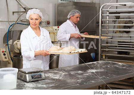 Female baker preparing shaped dough for proofing 64347172