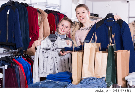 Smiling woman with daughter holding many bags Smiling woman with daughter holding many bags 64347365