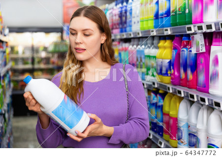 Young woman buying household chemicals or laundry detergent at supermarket Young woman buying household chemicals or laundry detergent at supermarket 64347772