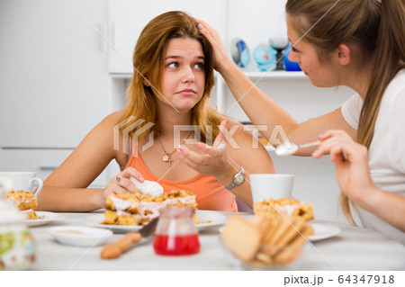woman with cake and calming sad friend 64347918