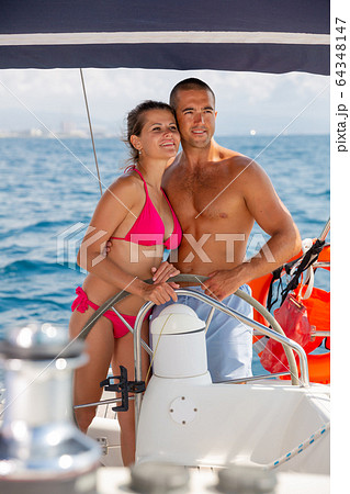 Man and woman steering pleasure yacht 64348147