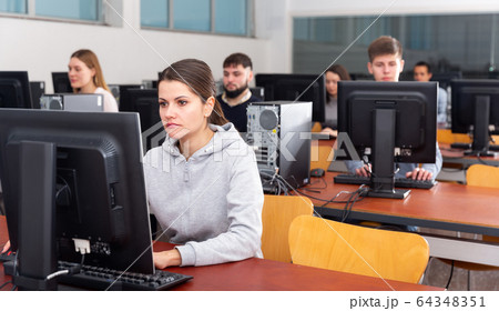Group of people of different ages learning to use computers in classroom 64348351