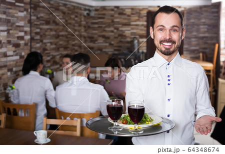 Waiter welcoming guests in restaurant 64348674