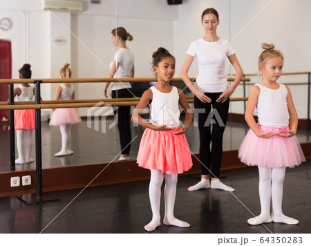 Dance teacher helping her little girls students Dance teacher helping her little girls students 64350283
