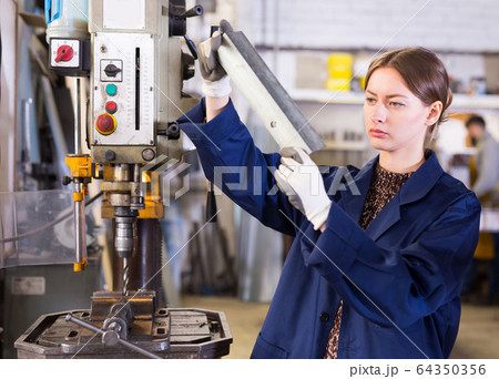 Woman worker in uniform working with metal beams 64350356