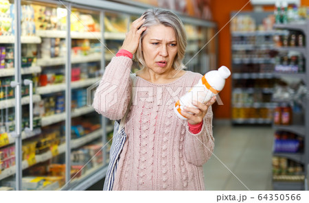 Shocked elderly female reading product label 64350566