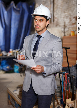 Man in helmet holding paper Man in helmet holding paper 64350694