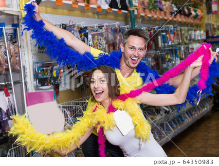 Happy young couple wearing feather boa 64350983