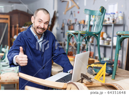 Craftsman looking at laptop in workshop 64351648