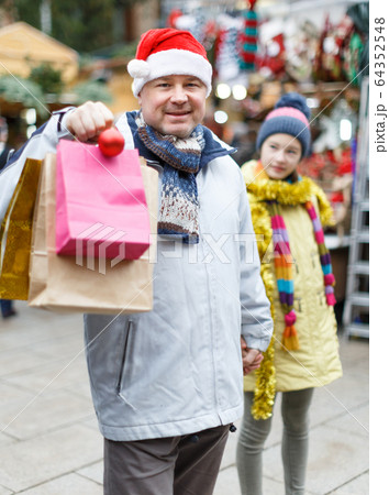 Smiling man in Santa hat with bags Smiling man in Santa hat with bags 64352548